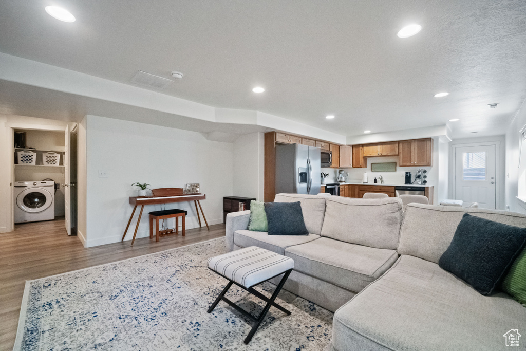 Living area with washer / dryer, light wood-type flooring, and recessed lighting