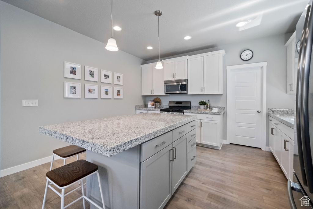 Kitchen with stainless steel appliances, a breakfast bar area, light wood-style flooring, a kitchen island, and recessed lighting