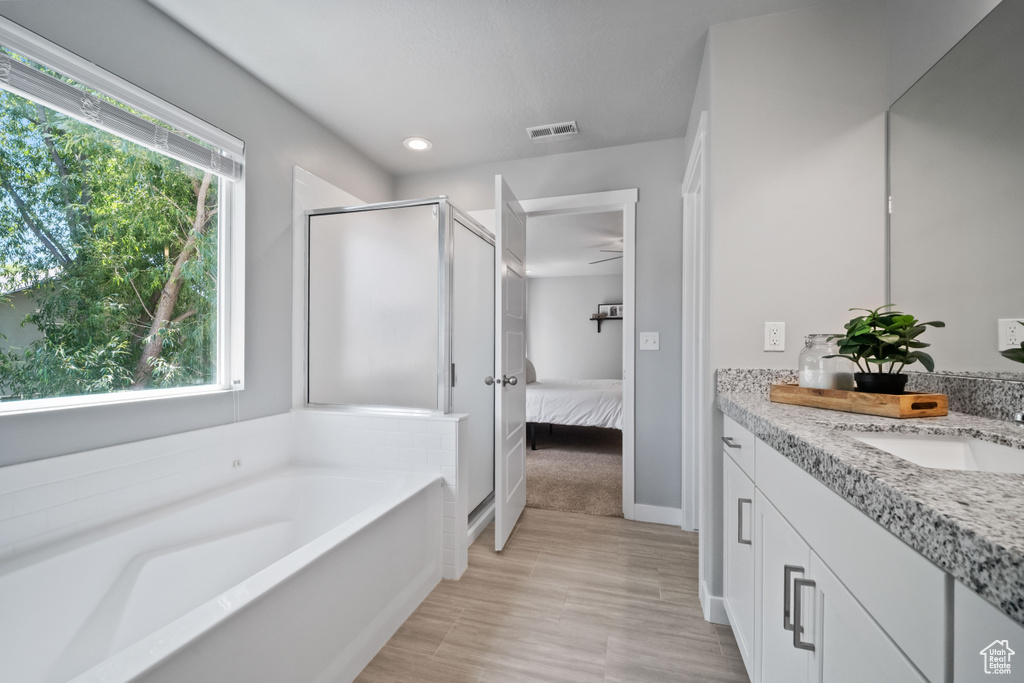 Ensuite bathroom featuring vanity, a stall shower, a garden tub, wood finished floors, and recessed lighting