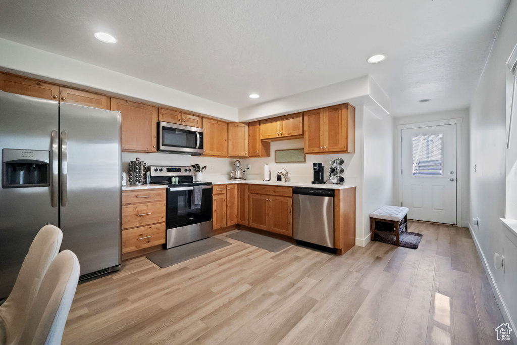 Kitchen featuring appliances with stainless steel finishes, light countertops, light wood-style floors, and recessed lighting