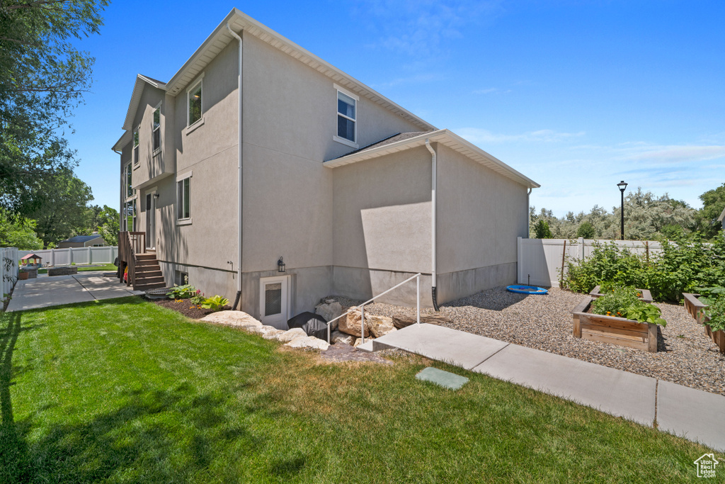 View of home\'s exterior featuring a garden, a fenced backyard, a patio area, and stucco siding