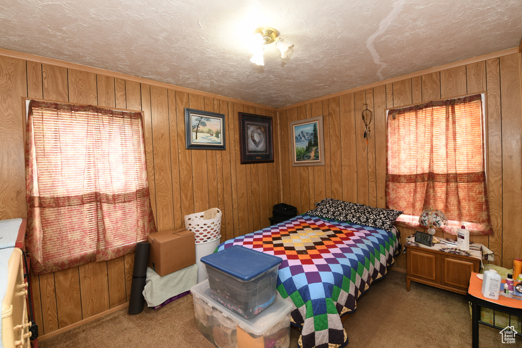 Carpeted bedroom with wood walls and a textured ceiling