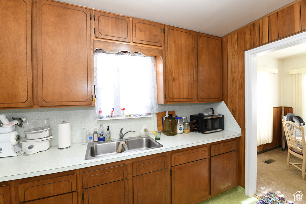 Kitchen with light countertops, stainless steel microwave, and brown cabinets