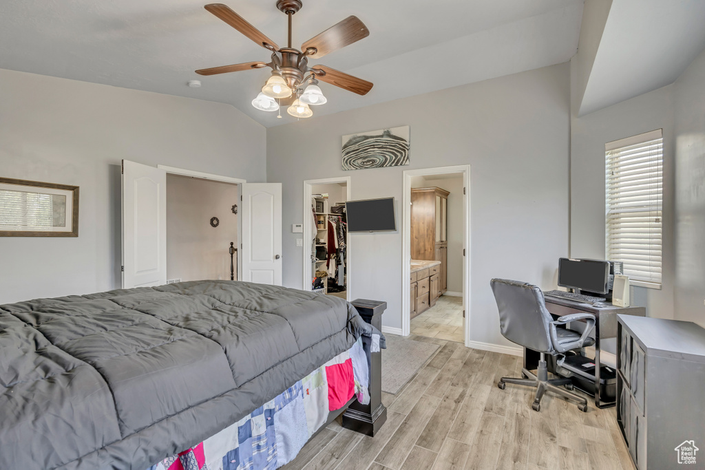 Bedroom with lofted ceiling, a walk in closet, light wood-style floors, a desk, and a closet