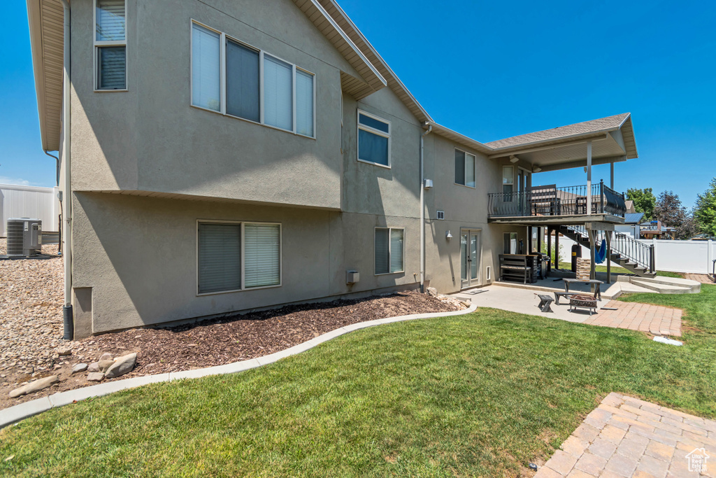Rear view of property featuring a patio, stucco siding, stairway, and an outdoor fire pit