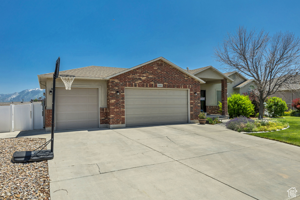 Ranch-style house with an attached garage, concrete driveway, brick siding, and a mountain view