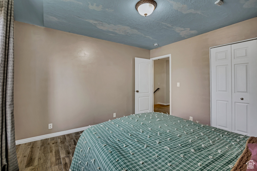 Bedroom with wood finished floors and a closet