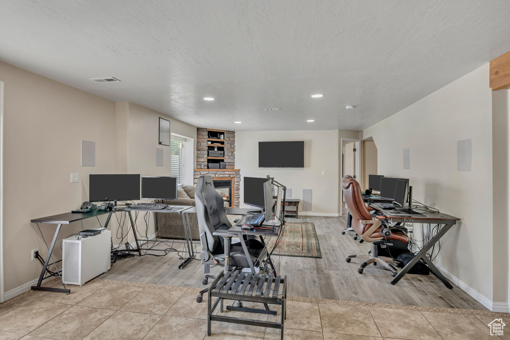 Home office featuring a stone fireplace, recessed lighting, and light wood-style flooring