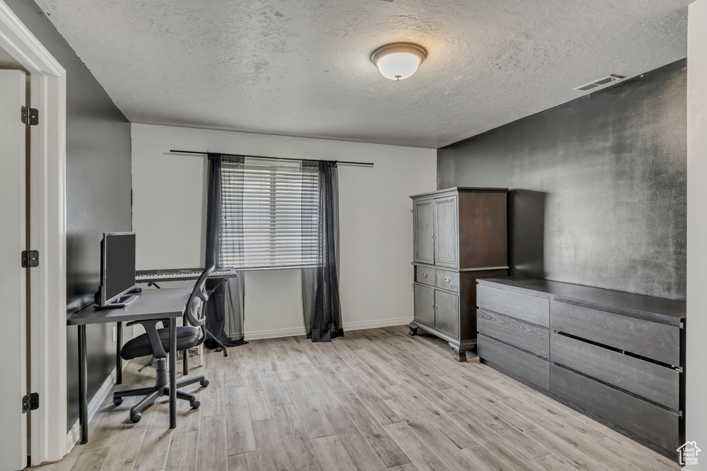Office with light wood finished floors and a textured ceiling
