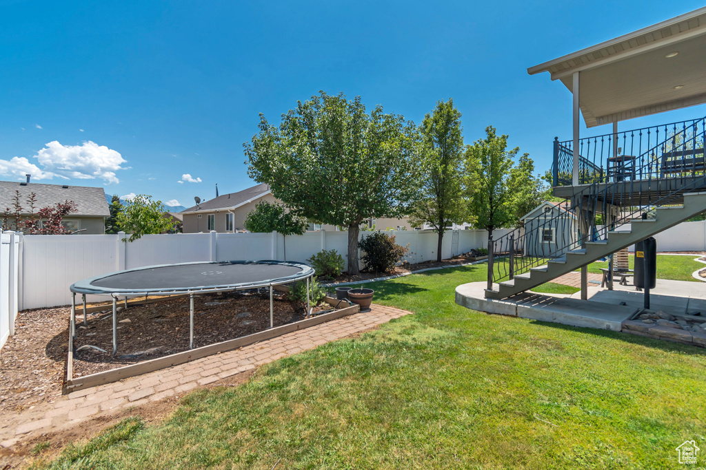 Fenced backyard featuring stairway, a trampoline, and a patio area