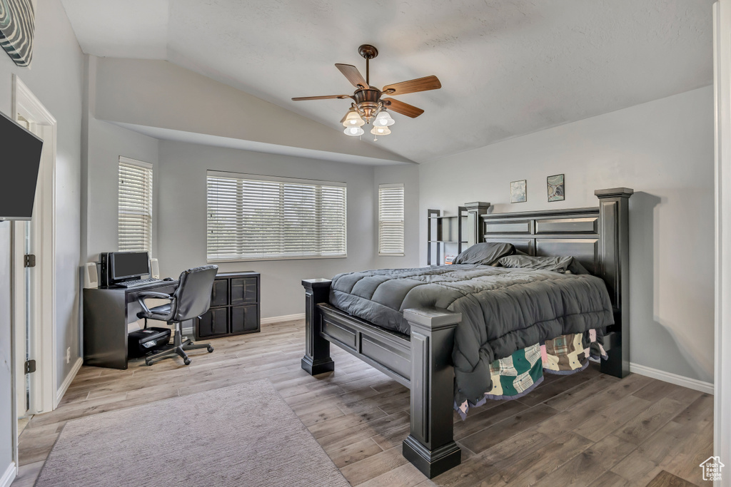 Bedroom featuring lofted ceiling, an office area, light wood-style floors, and ceiling fan