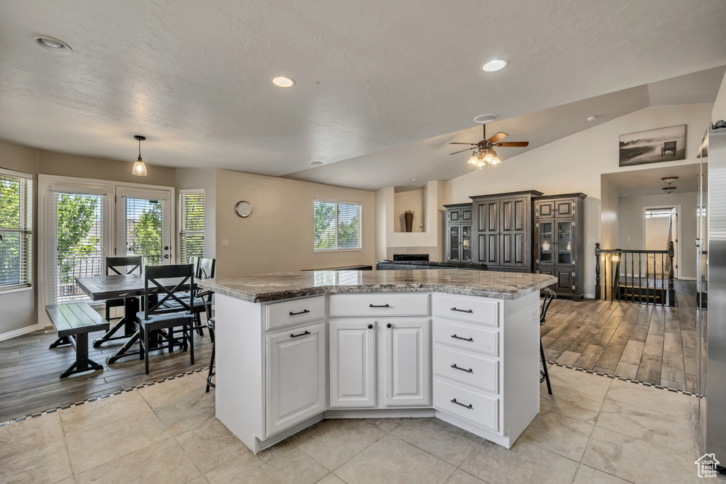 Kitchen with a kitchen island, a ceiling fan, white cabinets, recessed lighting, and lofted ceiling