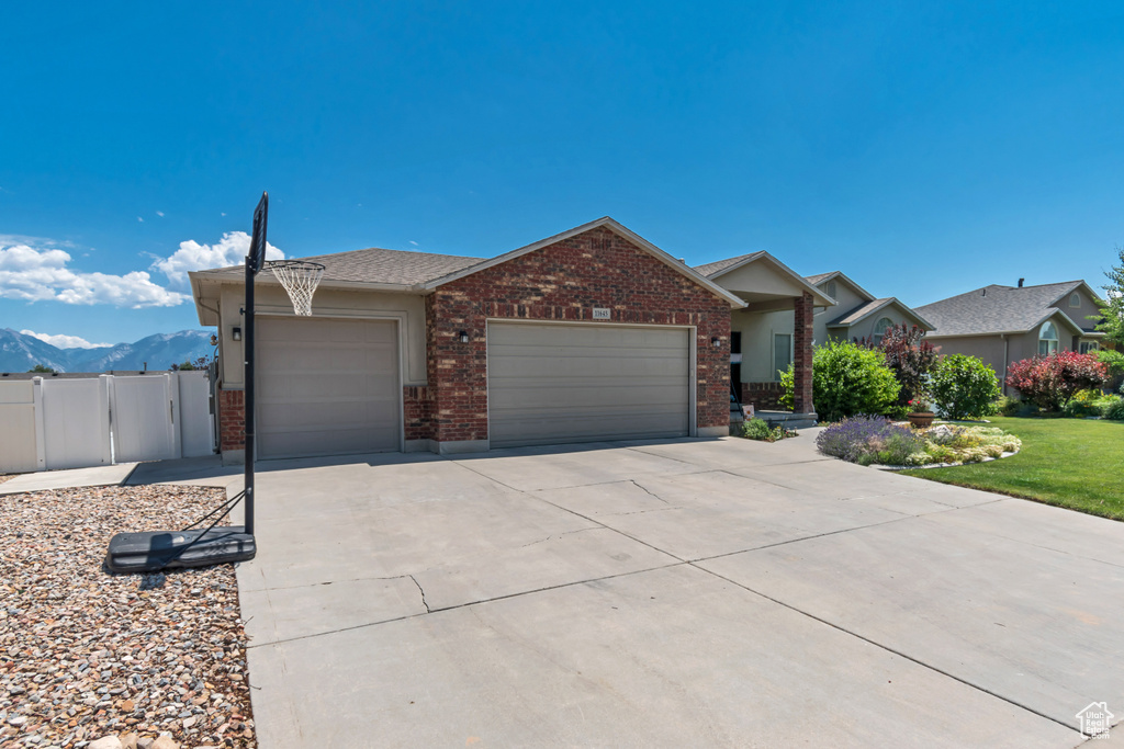 Ranch-style house featuring brick siding, an attached garage, driveway, and a mountain view