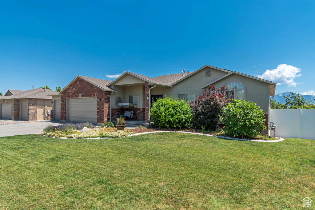 Ranch-style house with an attached garage, stucco siding, driveway, and brick siding