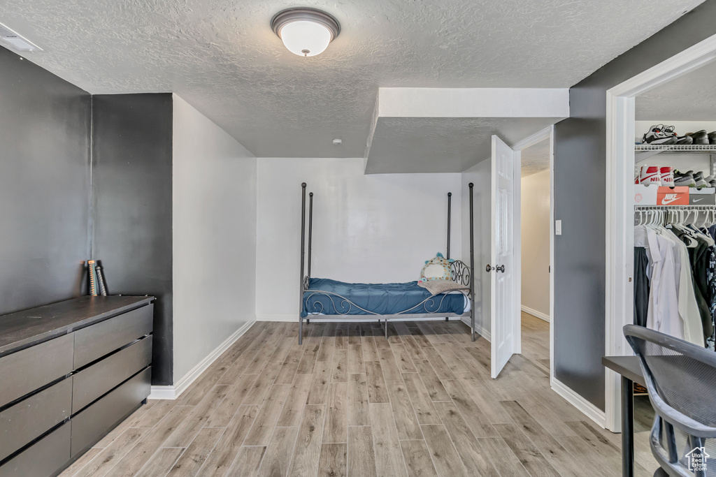 Bedroom featuring a textured ceiling, light wood-type flooring, and a closet