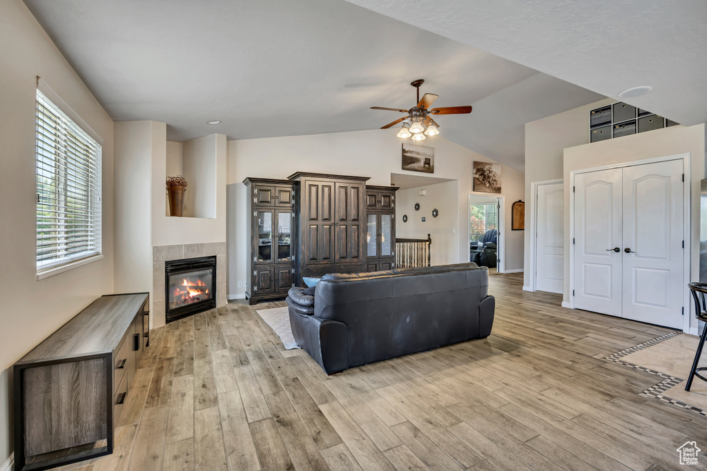 Living area featuring a ceiling fan, light wood-style flooring, plenty of natural light, and high vaulted ceiling