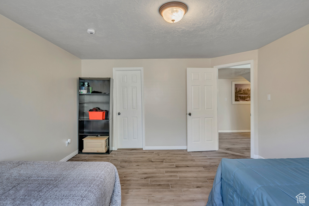 Bedroom featuring light wood finished floors, a closet, and a textured ceiling