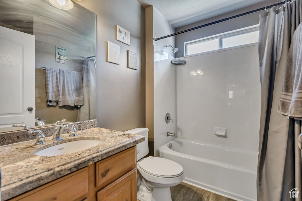Bathroom featuring shower / bath combination with curtain, wood finished floors, and vanity