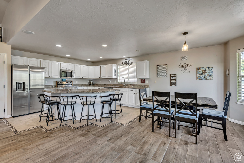 Dining space featuring light wood finished floors, recessed lighting, healthy amount of natural light, and a textured ceiling