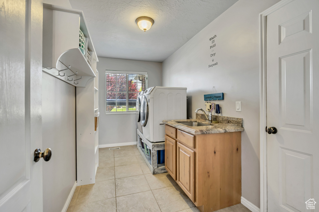 Washroom with light tile patterned floors, cabinet space, independent washer and dryer, and a textured ceiling
