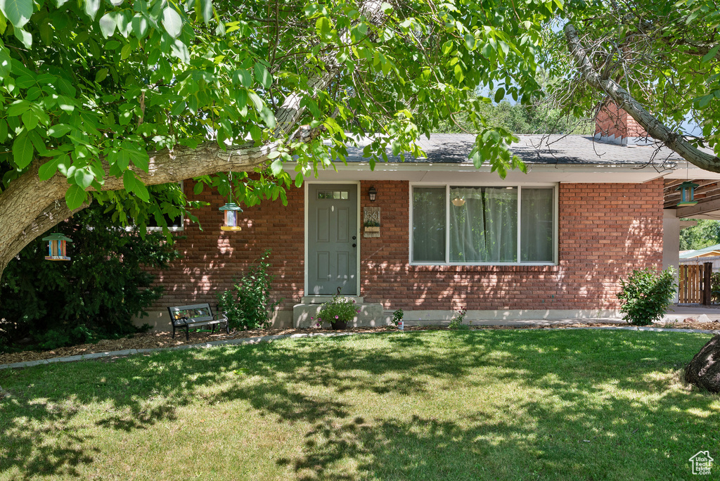 View of front of property featuring a front lawn and brick siding