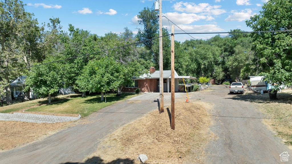 View of front of house featuring a chimney, a front yard, and driveway