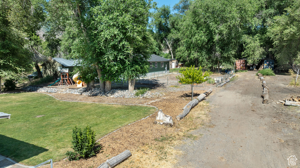 View of grassy yard featuring a playground and view of wooded area