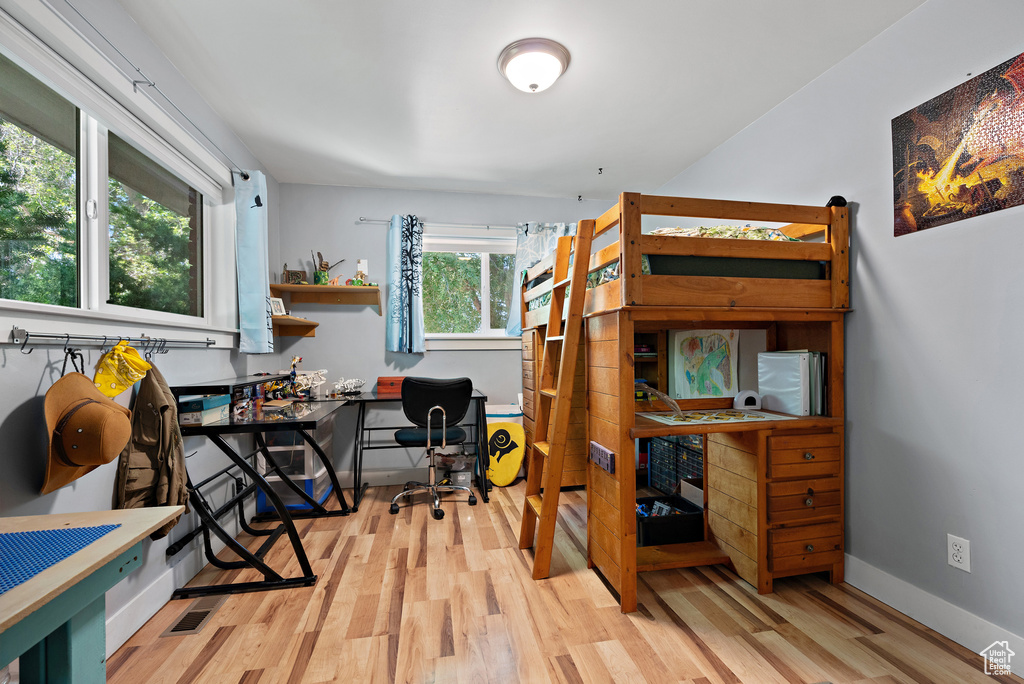 Bedroom with light wood finished floors and an office area