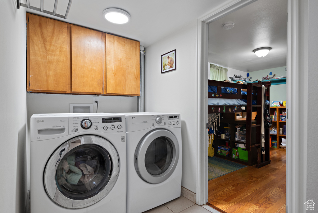 Washroom featuring washing machine and clothes dryer, cabinet space, and light tile patterned floors