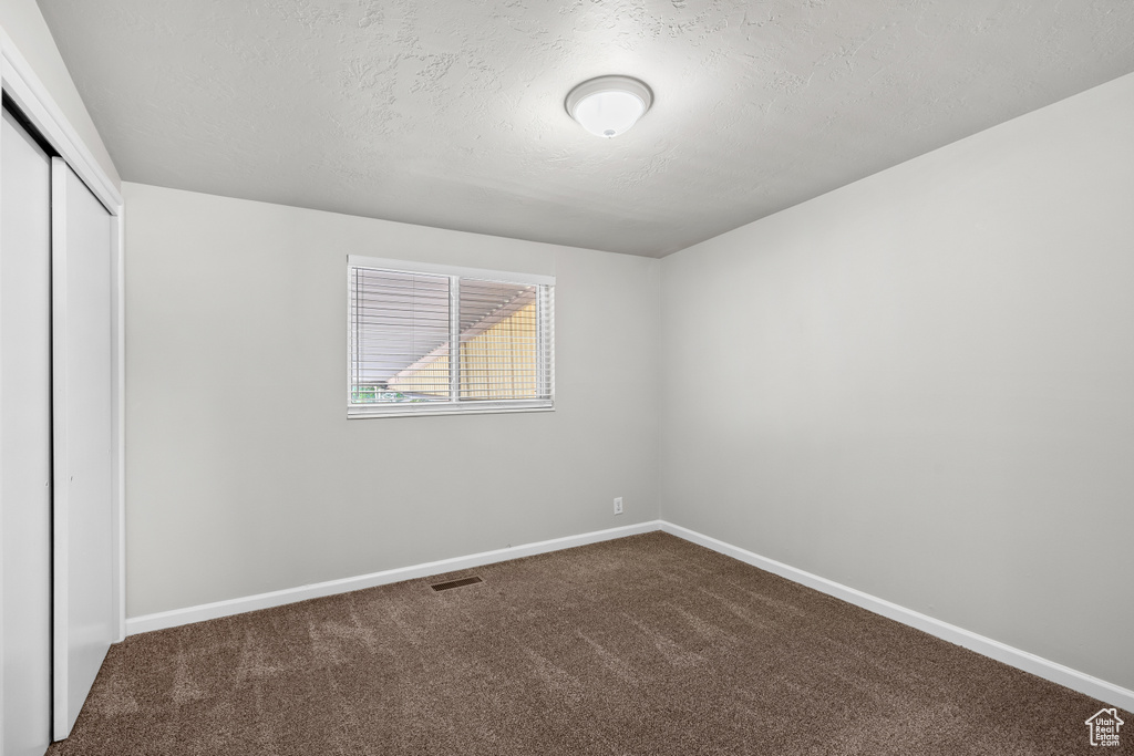 Unfurnished bedroom featuring a closet, carpet floors, and a textured ceiling