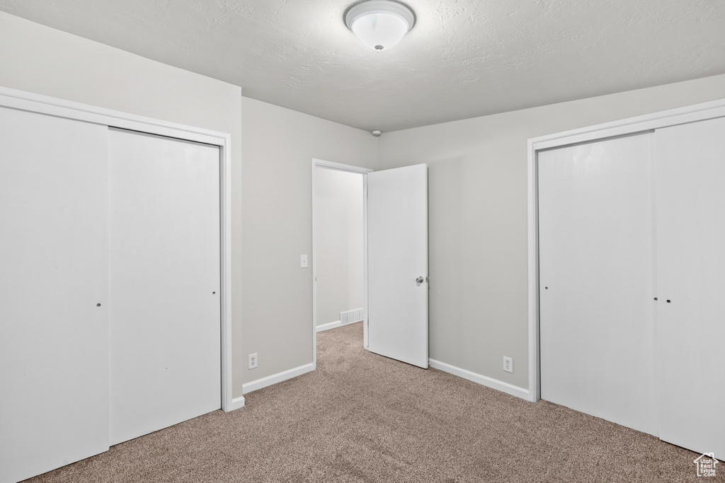 Unfurnished bedroom featuring carpet floors and multiple closets