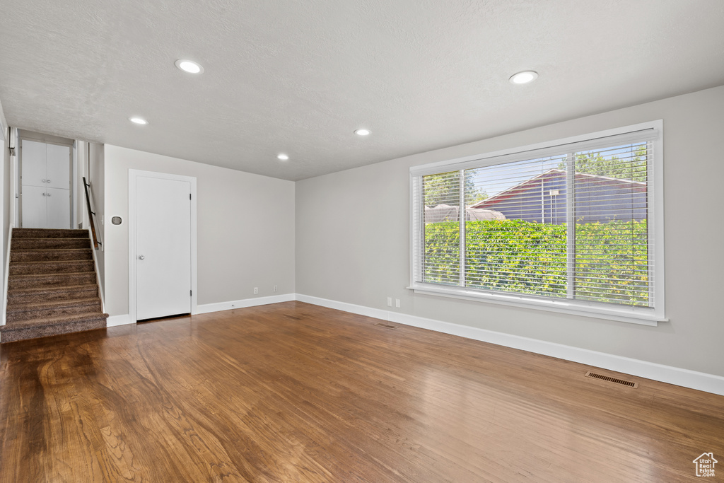 Unfurnished room with stairs, dark wood-style flooring, and recessed lighting