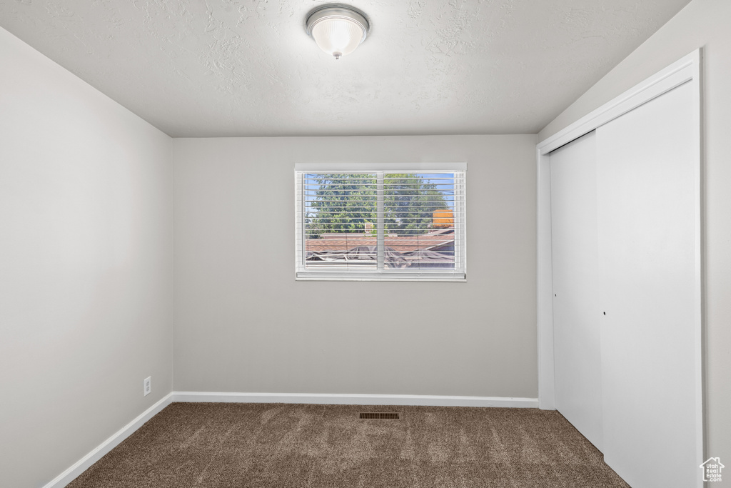 Unfurnished bedroom with carpet flooring, a closet, and a textured ceiling