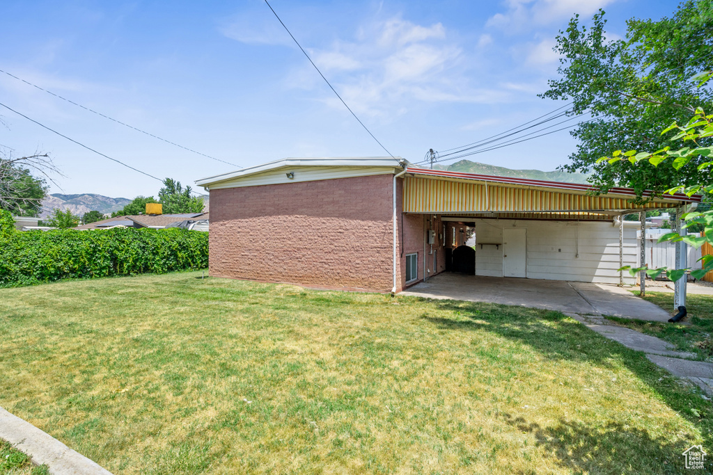 View of home\\\'s exterior featuring an attached carport, a lawn, a mountain view, and brick siding