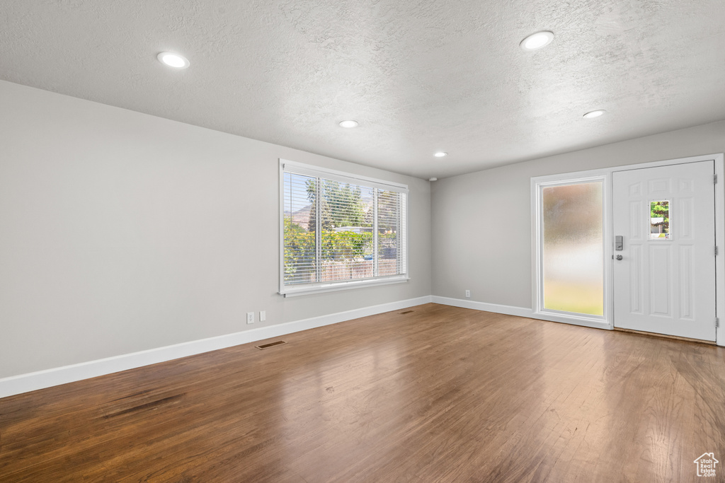 Empty room featuring a textured ceiling, wood finished floors, and recessed lighting