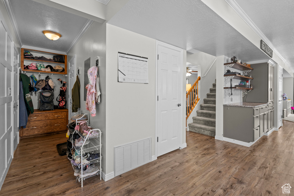 Foyer featuring ornamental molding, wood finished floors, stairs, and a textured ceiling