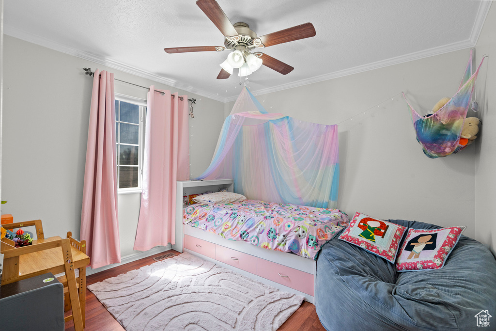 Bedroom featuring wood finished floors, crown molding, and ceiling fan