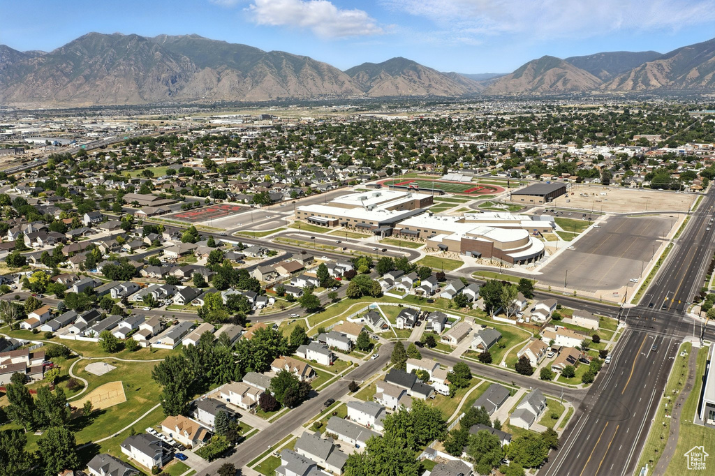 Aerial view of property and surrounding area featuring a mountainous background and nearby suburban area