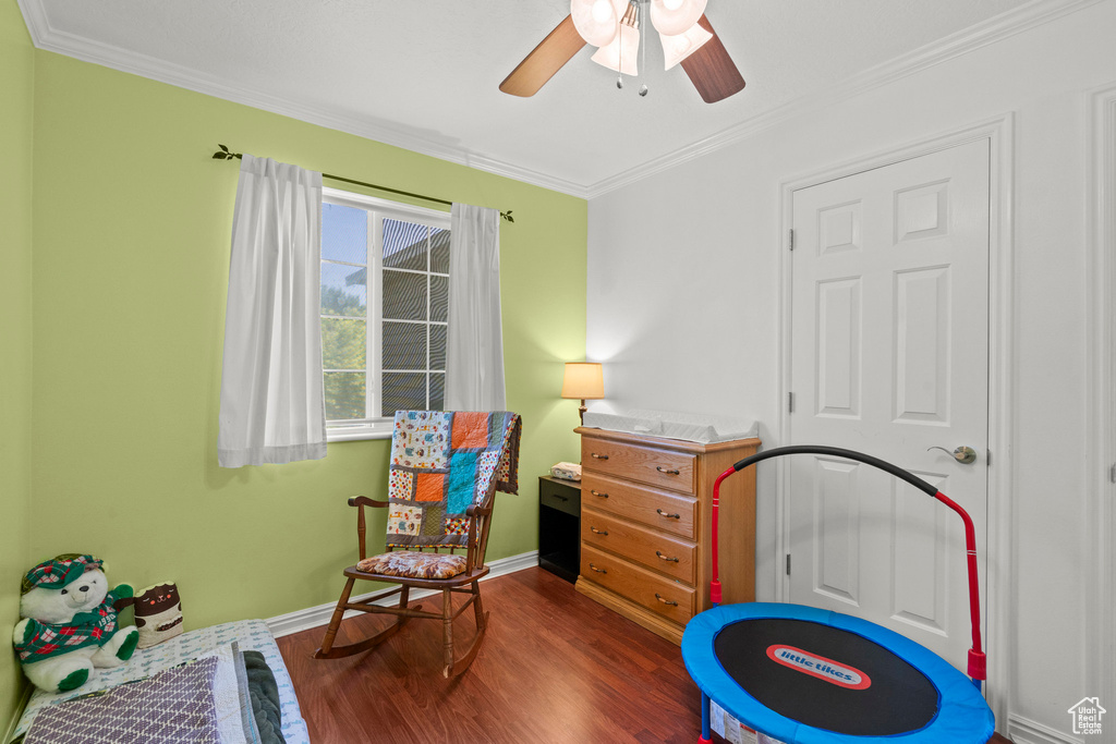 Playroom with dark wood finished floors, ornamental molding, and ceiling fan