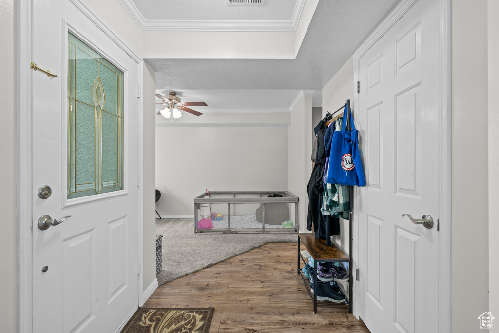 Entryway with wood finished floors, ornamental molding, and ceiling fan