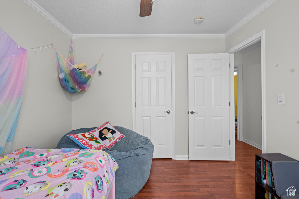 Bedroom with crown molding, wood finished floors, and ceiling fan