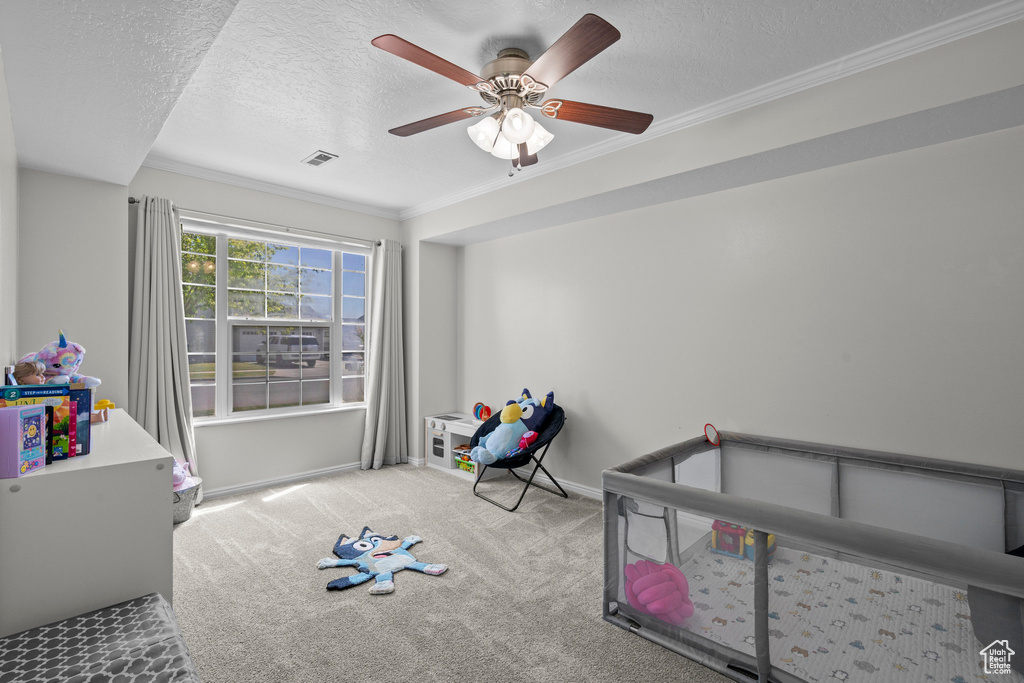 Unfurnished bedroom featuring carpet, a textured ceiling, crown molding, and a ceiling fan