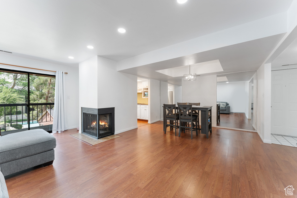 Living room with wood finished floors, recessed lighting, and a multi sided fireplace