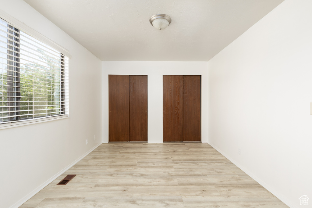 Unfurnished bedroom featuring two closets and light wood-type flooring