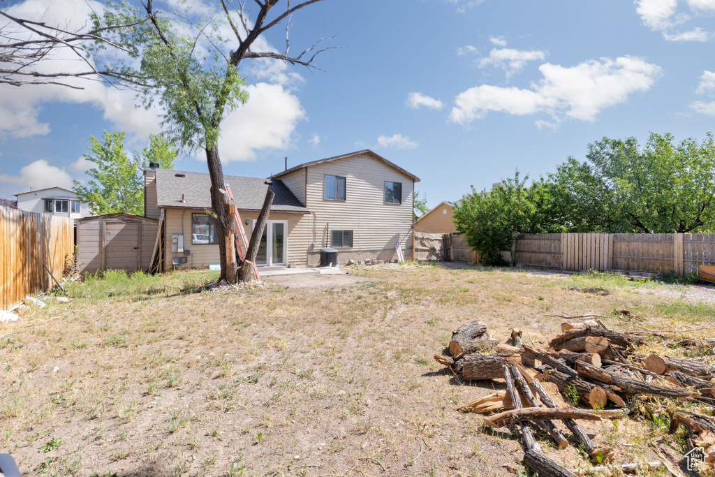 Back of house featuring a storage shed, a fenced backyard, a patio, and a chimney