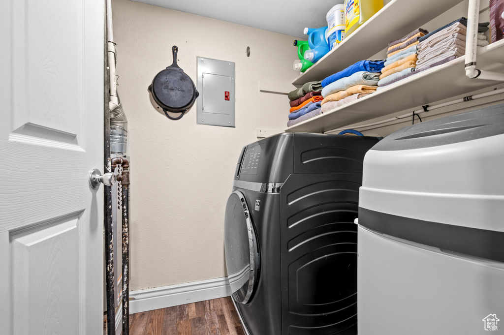 Laundry area featuring electric panel and dark wood-style floors