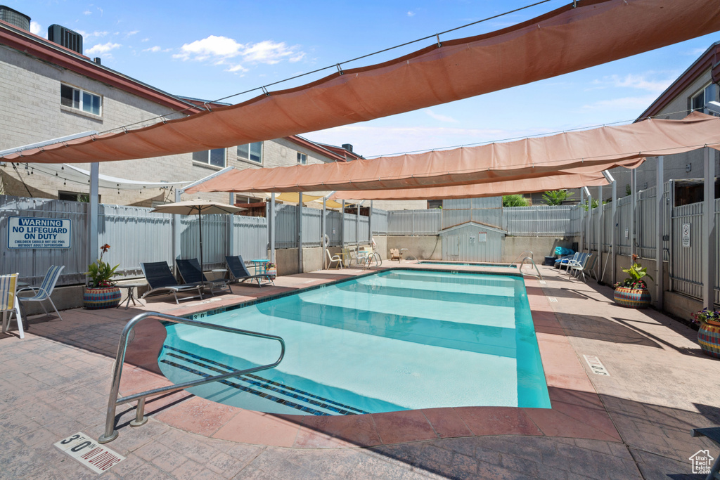 Community pool featuring a patio area and a fenced backyard