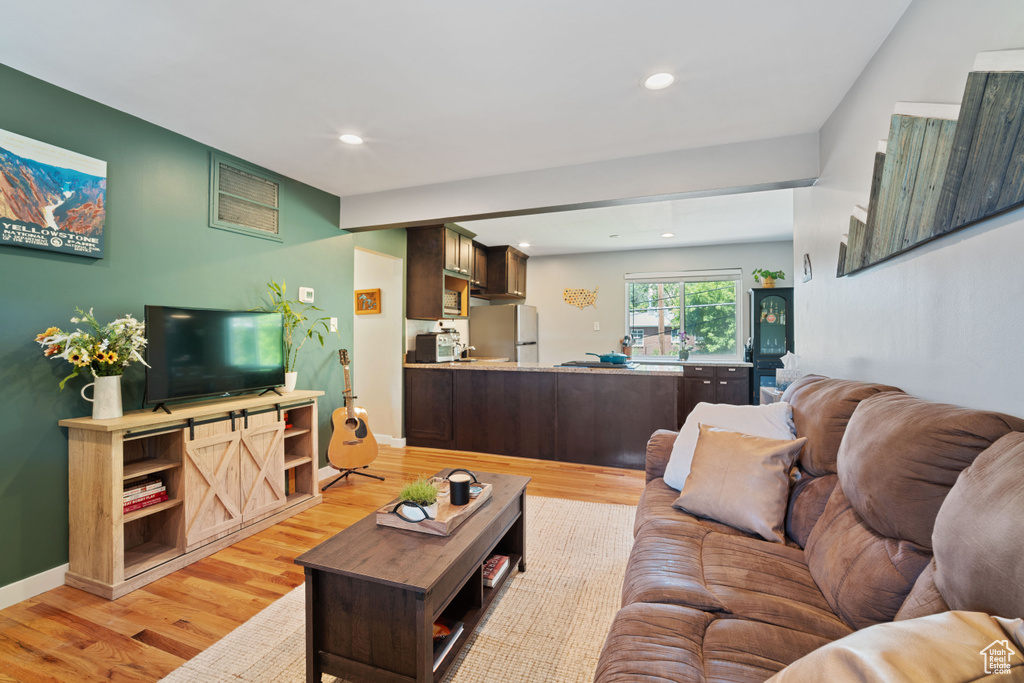 Living room with light wood-style flooring and recessed lighting