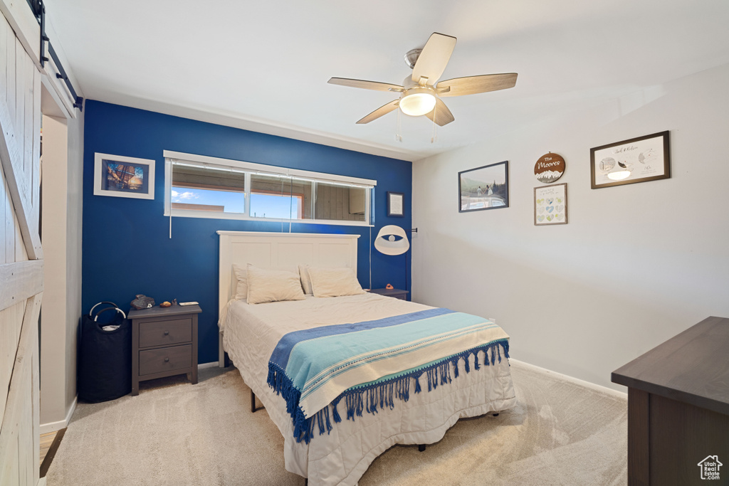 Bedroom featuring a barn door, carpet, and a ceiling fan