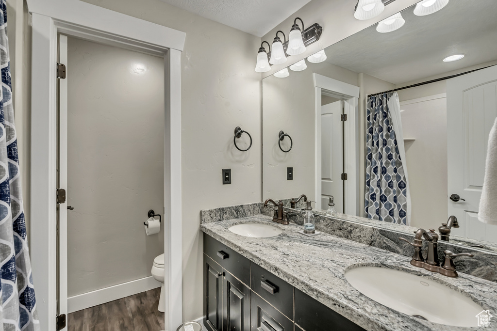 Bathroom featuring wood finished floors, double vanity, and a shower with curtain